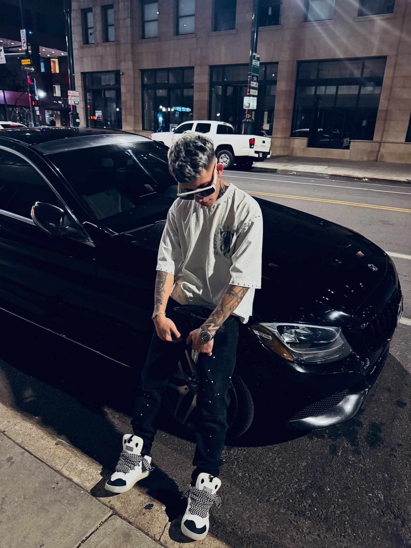 Milian standing beside a black car on a downtown street